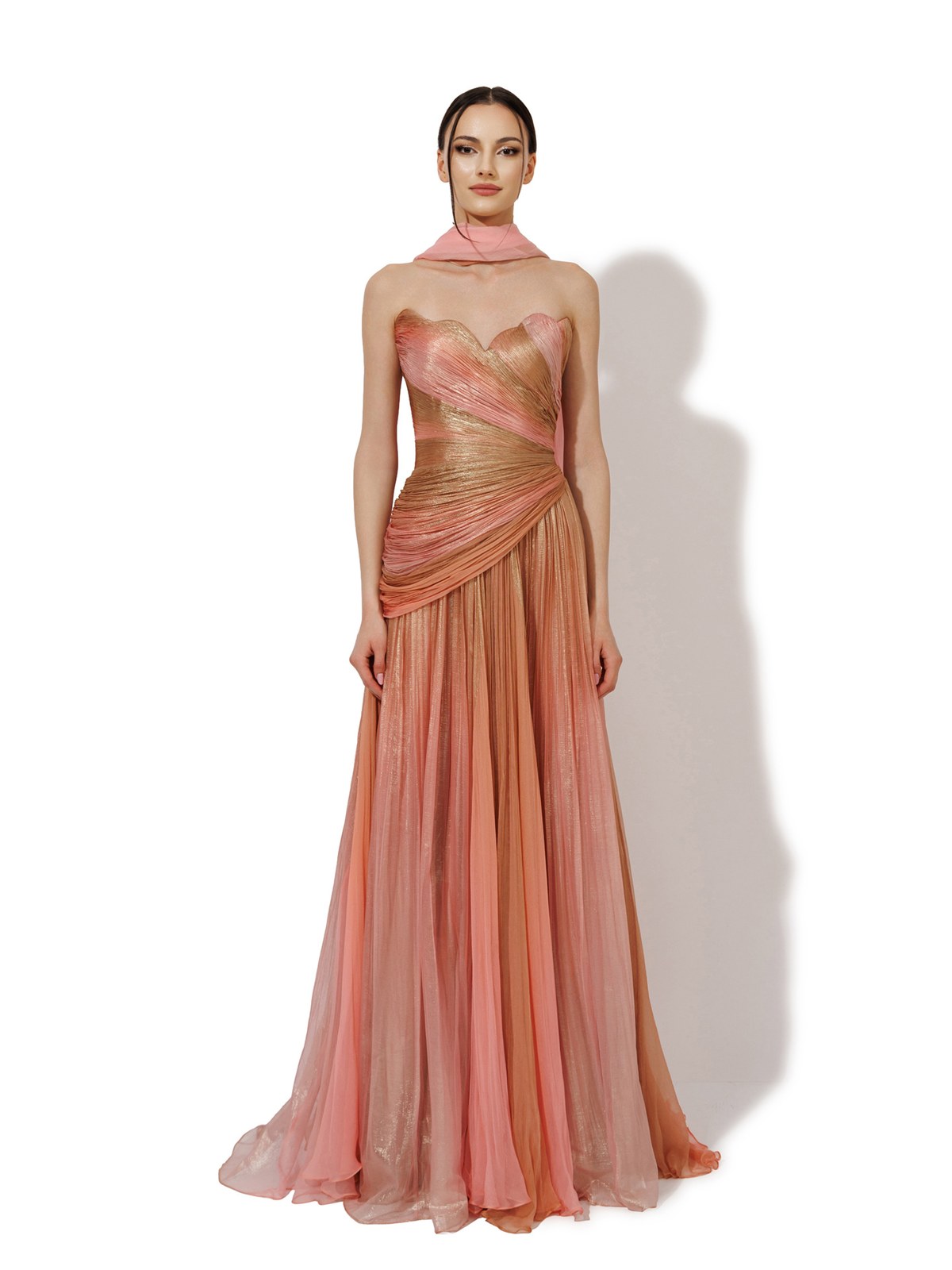 Model in a coral gold draped gown with a high neck scarf
