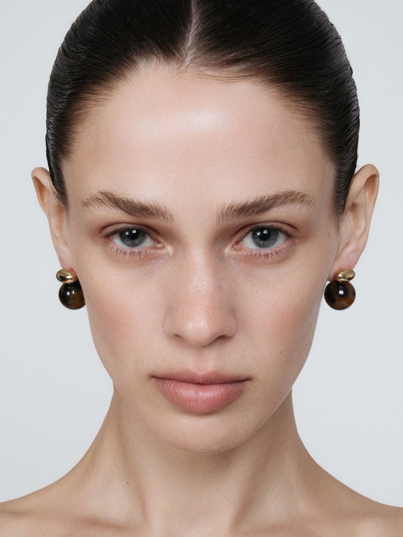 Model wearing round dark SHASHI stud earrings in a studio portrait