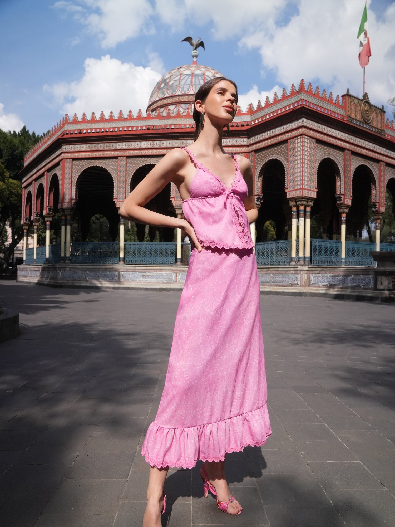Model in a pink ruffle hem linen look set in front of an ornate pavilion