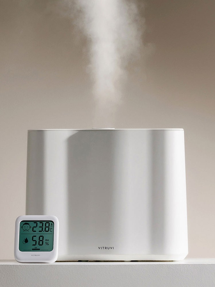 White Vitruvi humidifier on a pale pedestal beside a humidity display