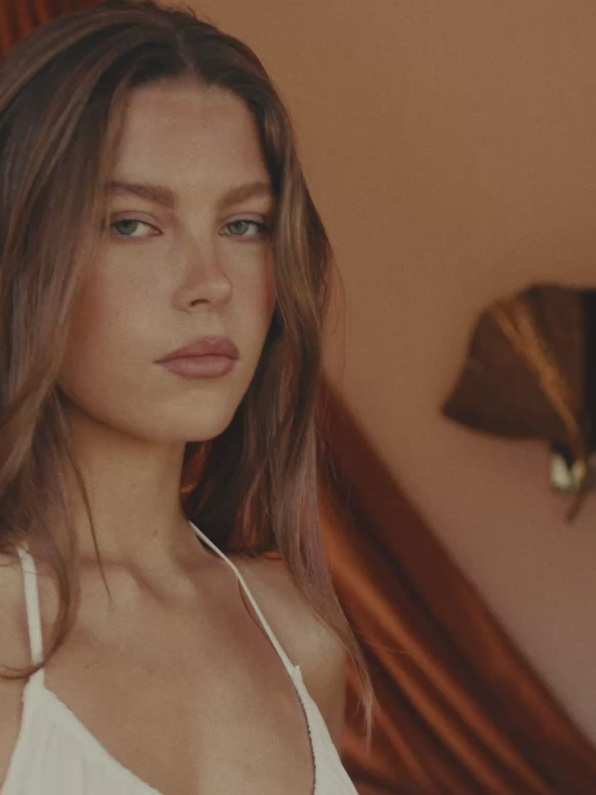 Close portrait of a model in a white top in a warm-toned room