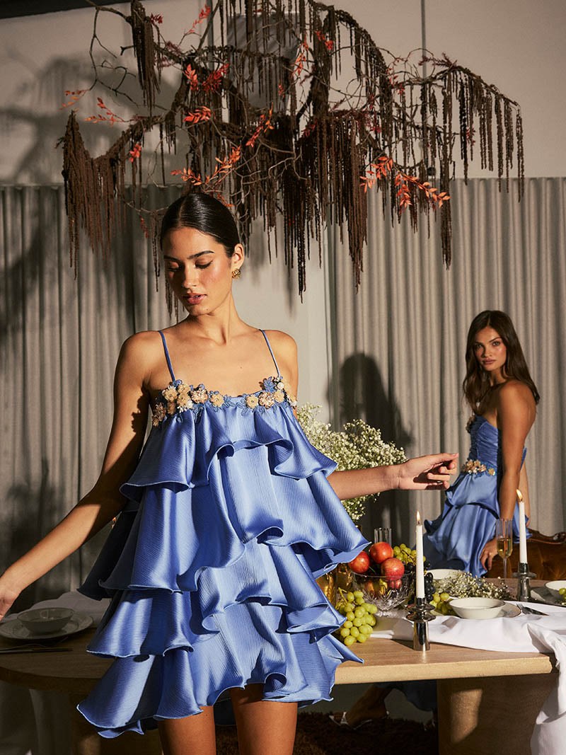 Model in a blue ruffled ELLIATT dress at a candlelit table