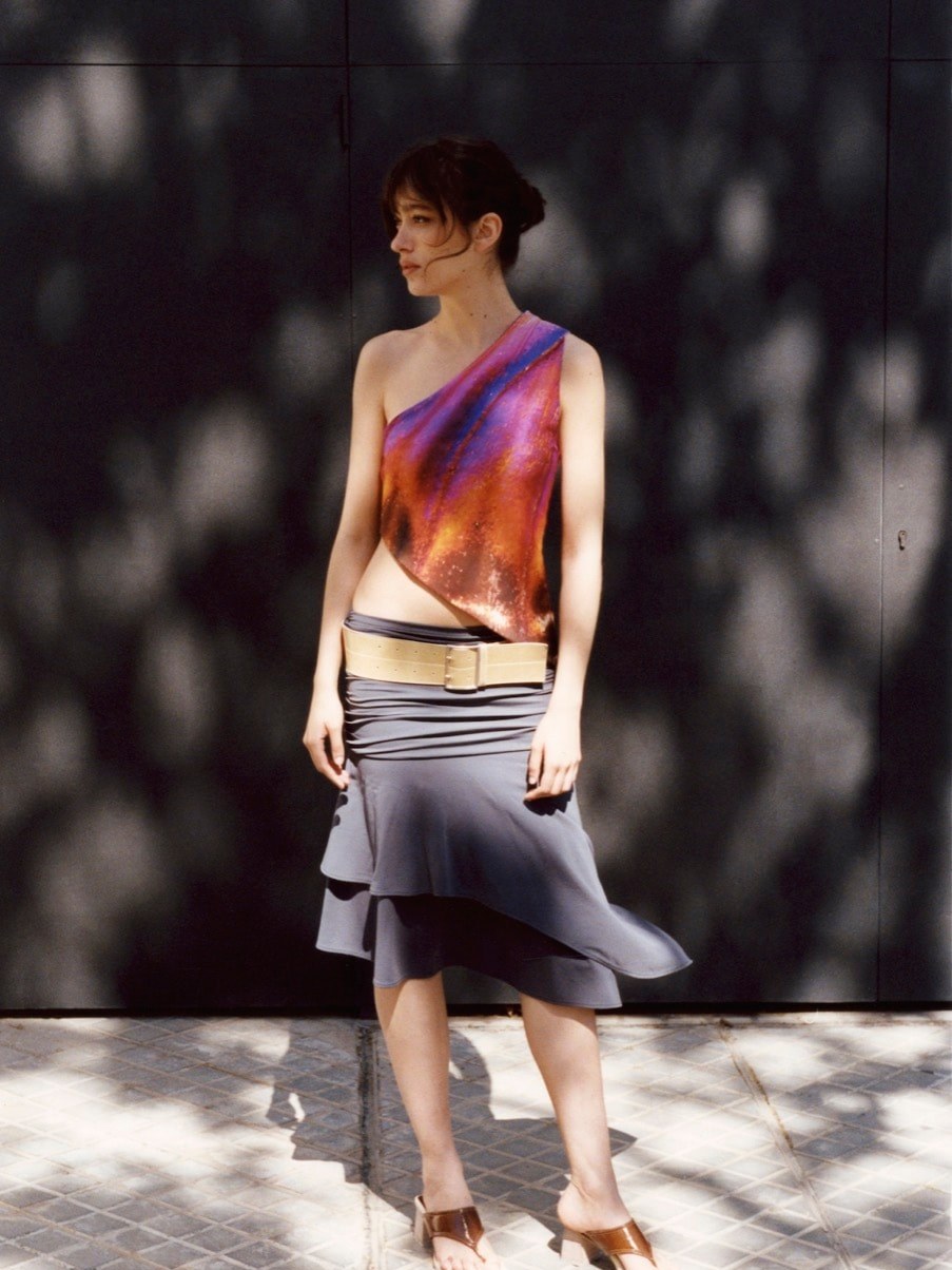 Feners campaign model in a colorful top and gray skirt outdoors