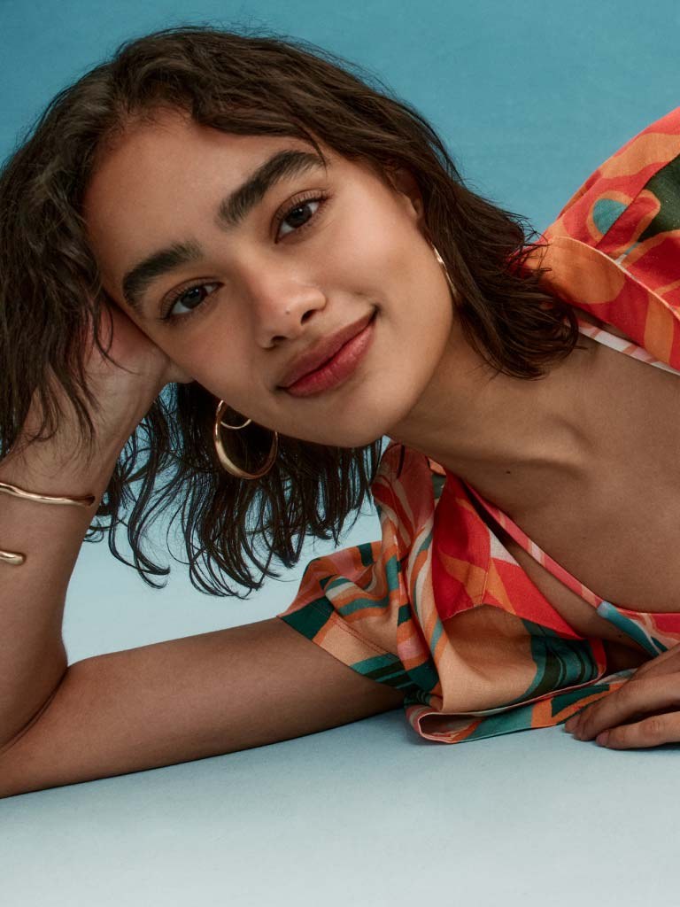 Model in a colorful printed beach shirt against a blue studio backdrop