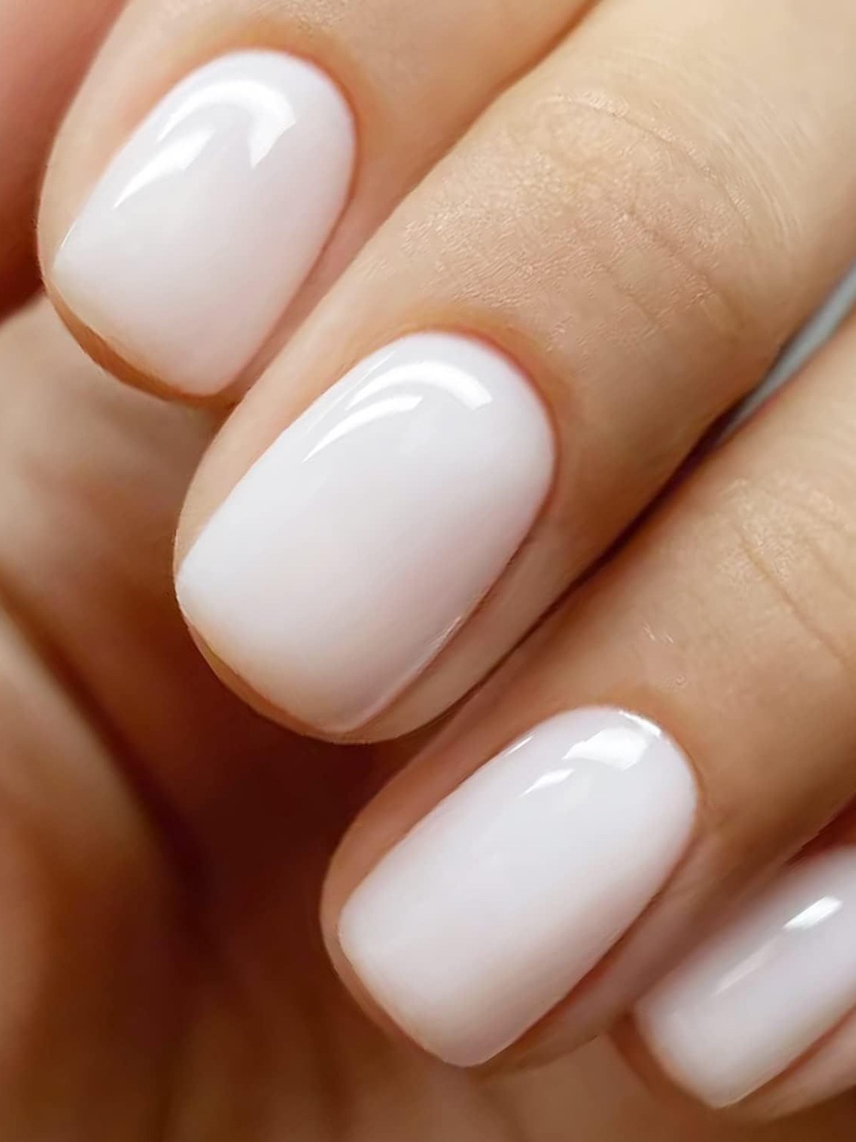 Short rounded nails in a glossy milky white polish