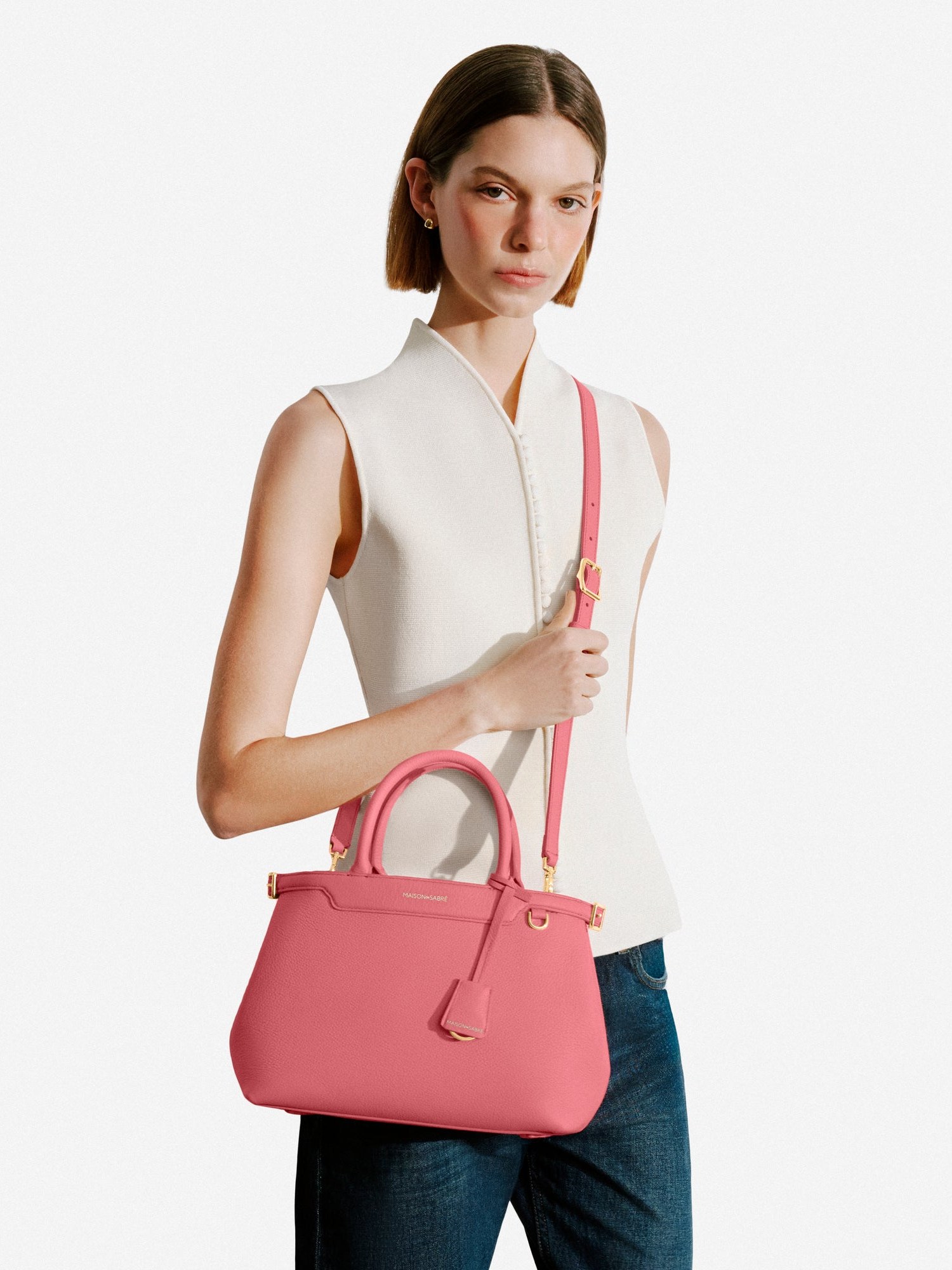 Model in a white sleeveless top and jeans with a candy pink Palais crossbody
