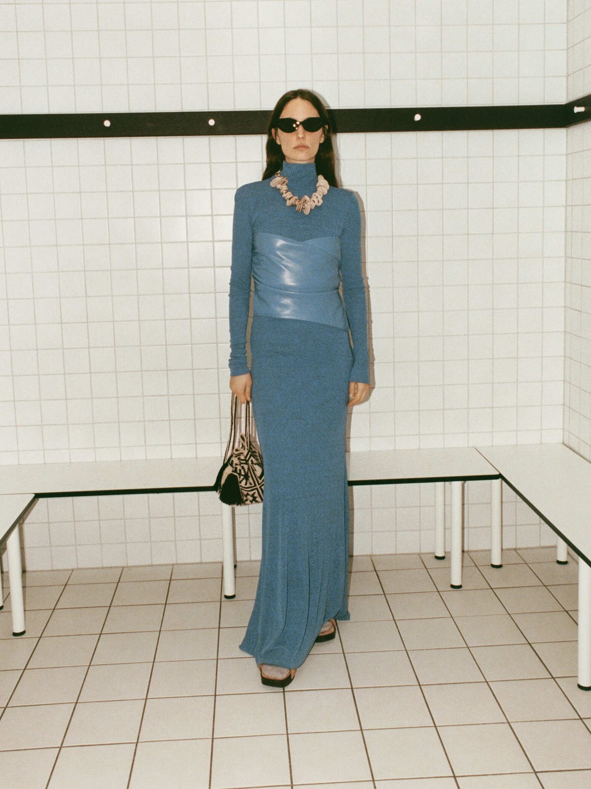 Model in a long blue dress in a tiled interior