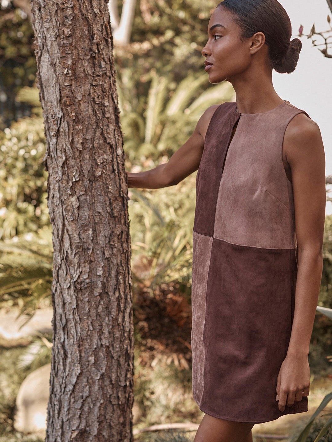 Model in a brown MISA dress standing by a tree