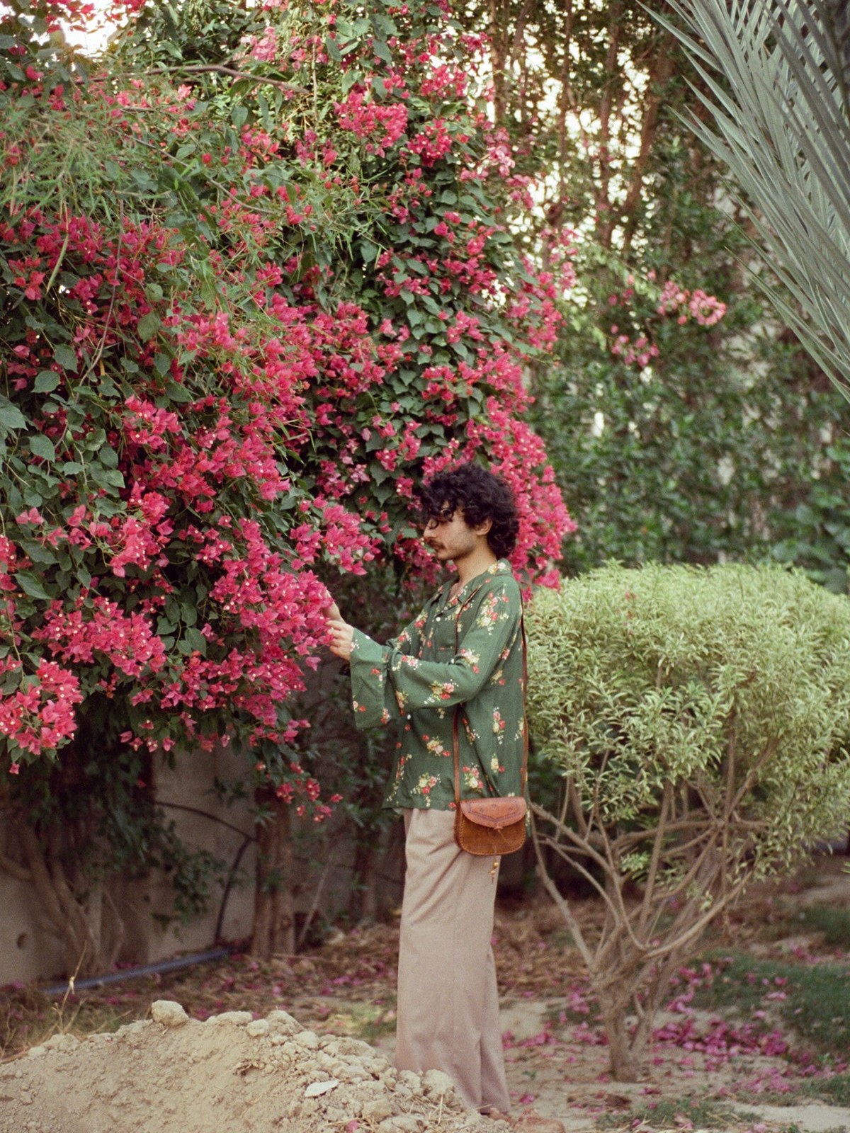 Model in a green embroidered outfit among flowering bushes