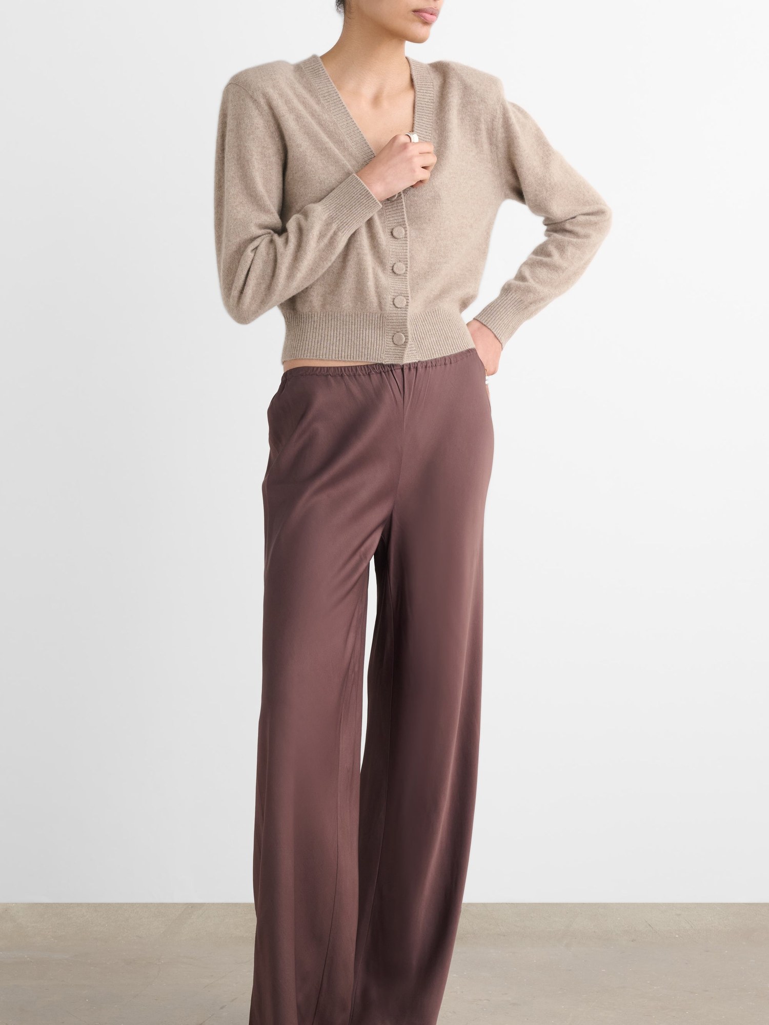 Model in a taupe V neck cardigan and wide brown trousers
