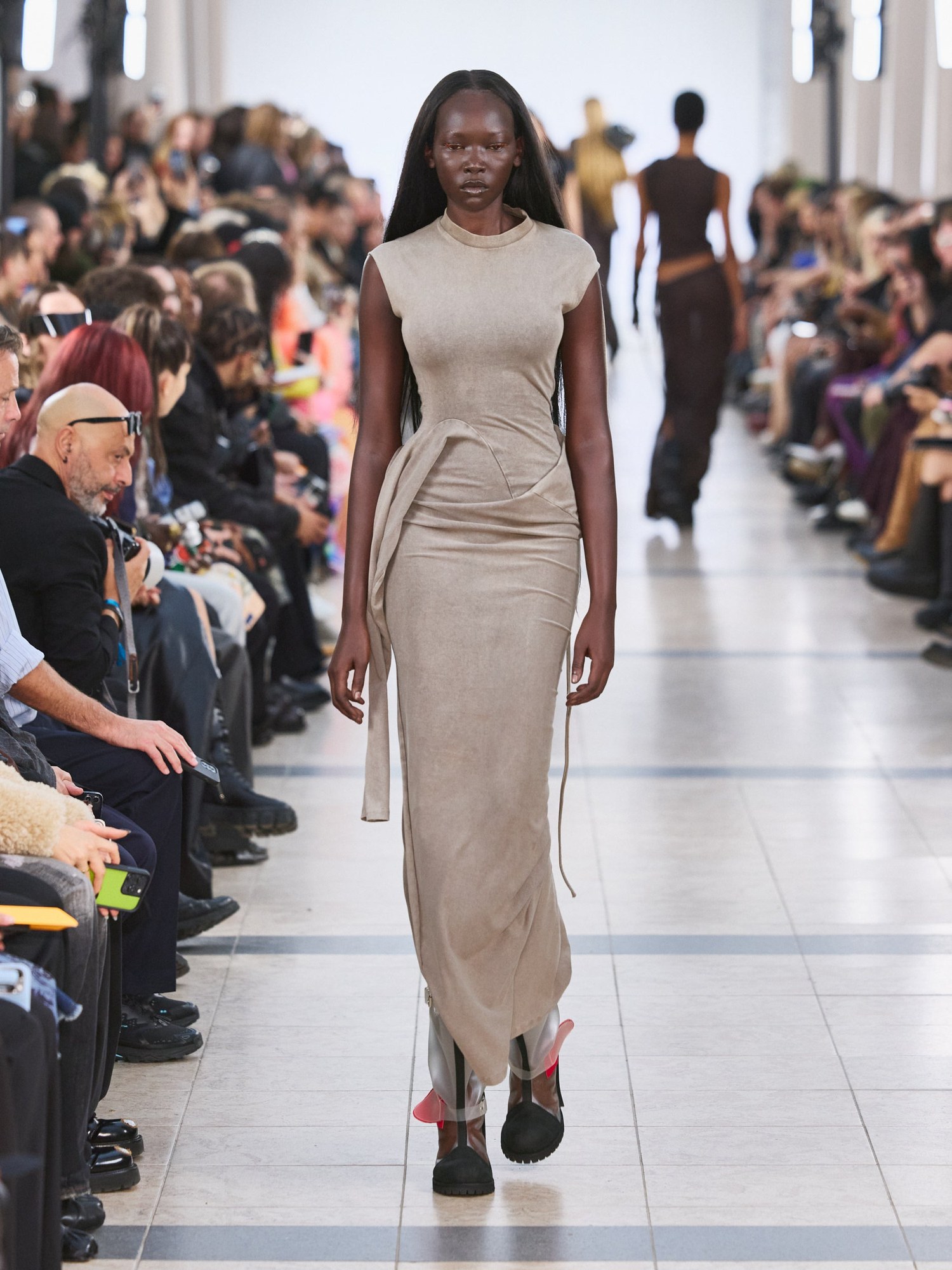 Runway model in a draped taupe sleeveless maxi dress