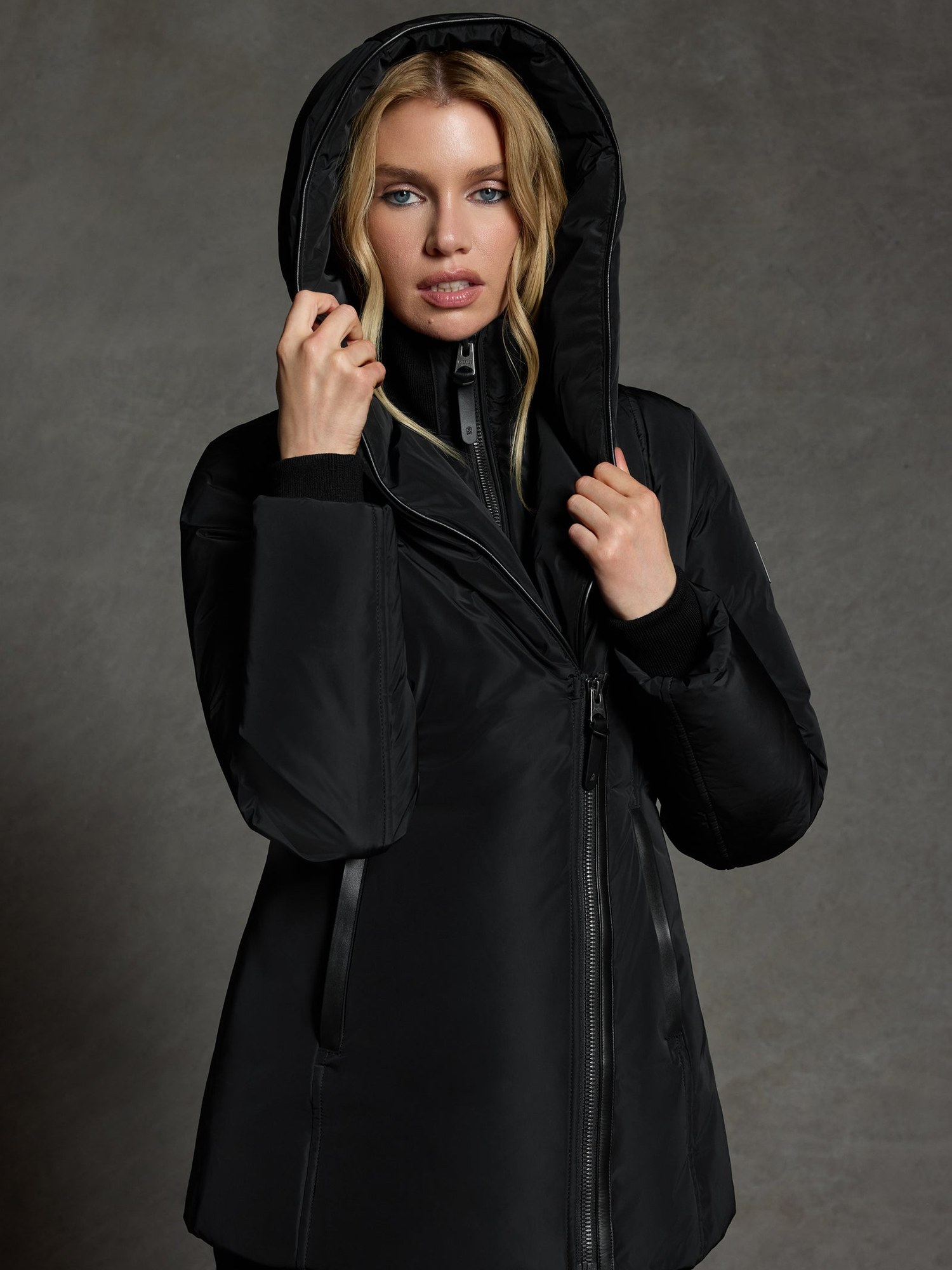 Blonde model with the hood up in a black down jacket