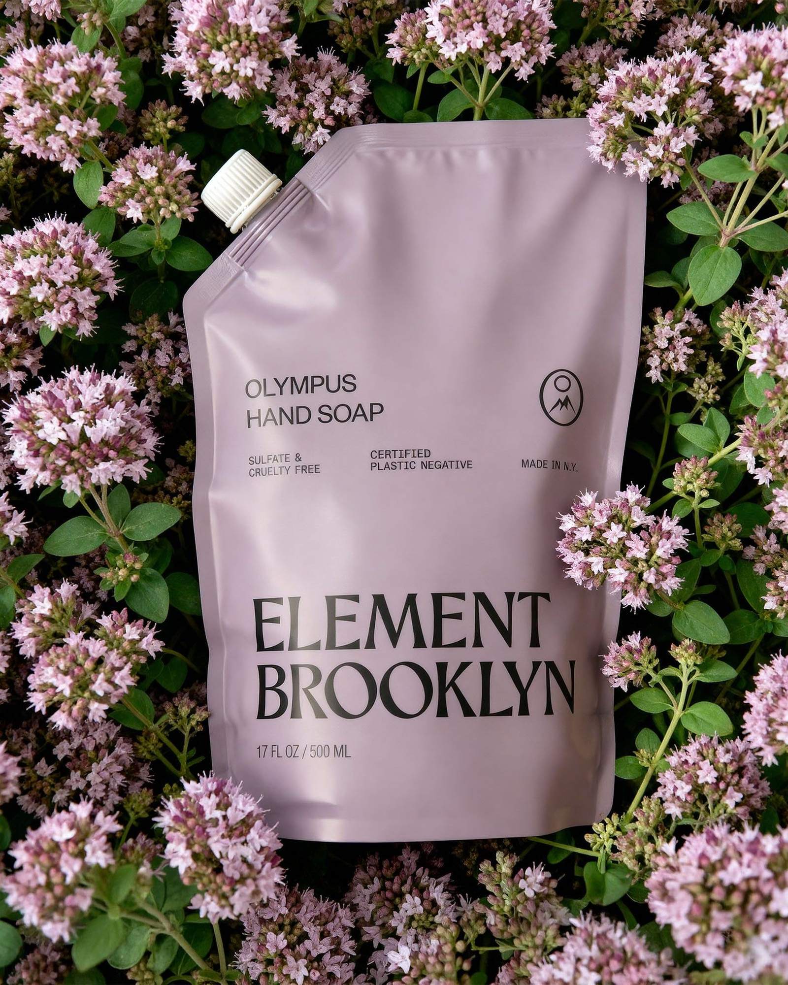 Lilac Element Brooklyn Olympus Hand Soap refill pouch resting on a bed of purple wildflowers