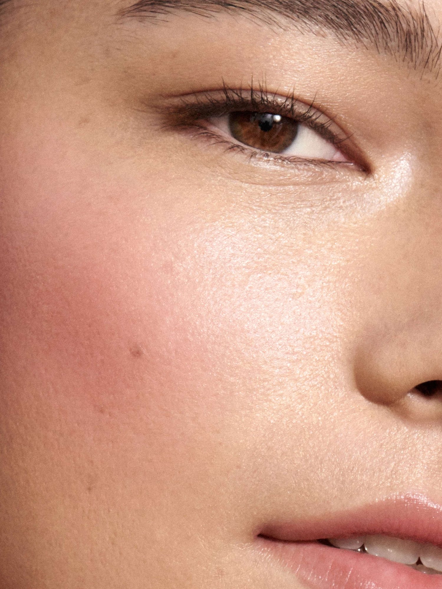 Tight crop of a cheek with blush and glowing skin
