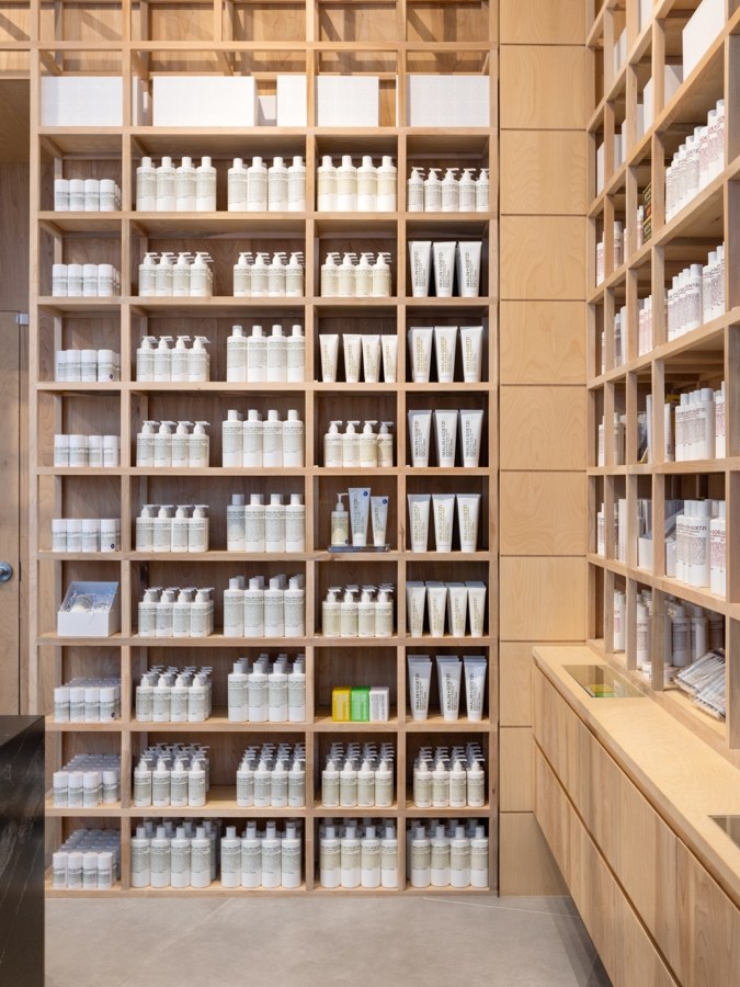 A close view of neatly arranged products on wooden shelves inside a MALIN+GOETZ apothecary