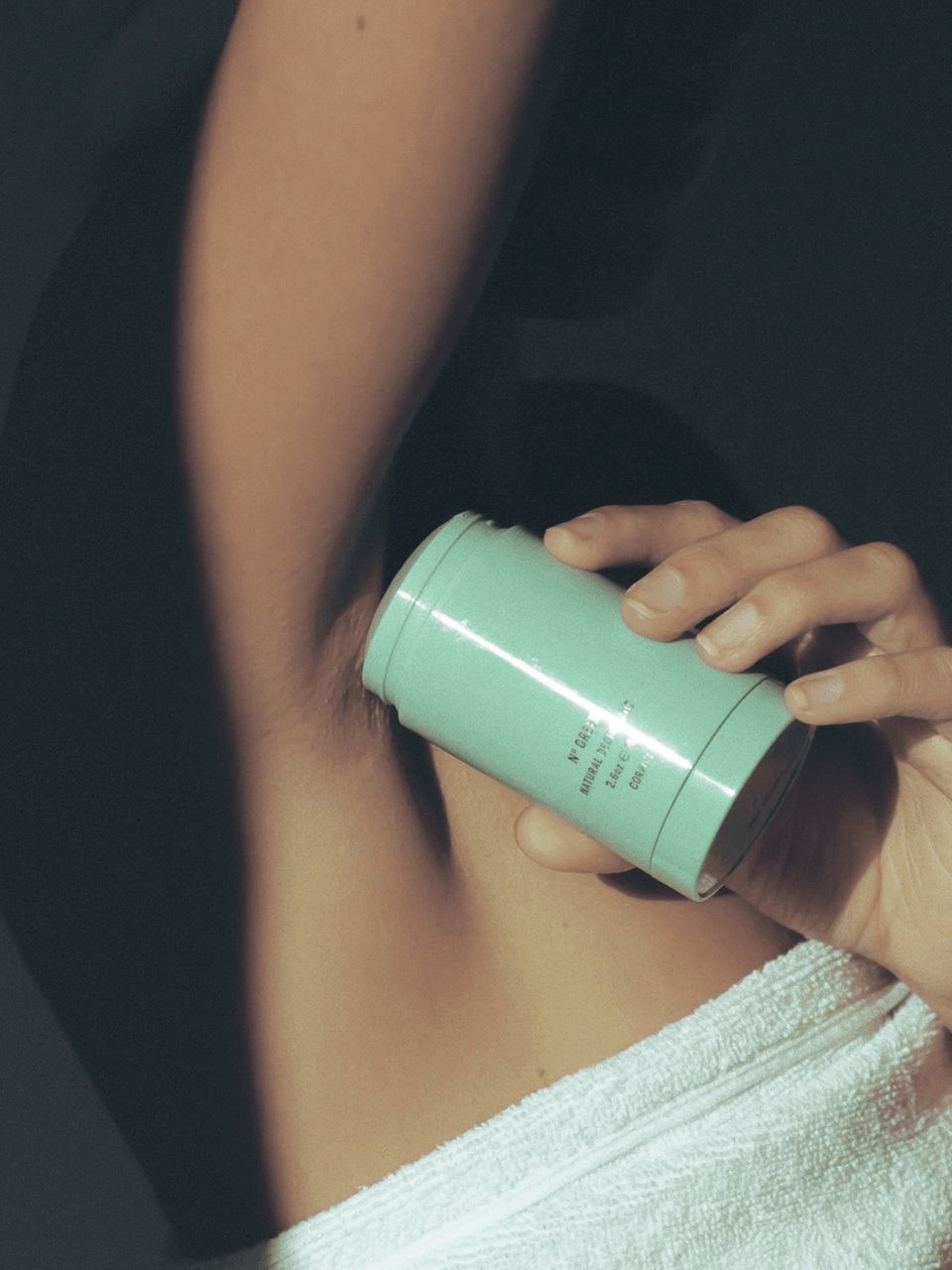 Hand applying a sea-green Corpus deodorant stick to an underarm
