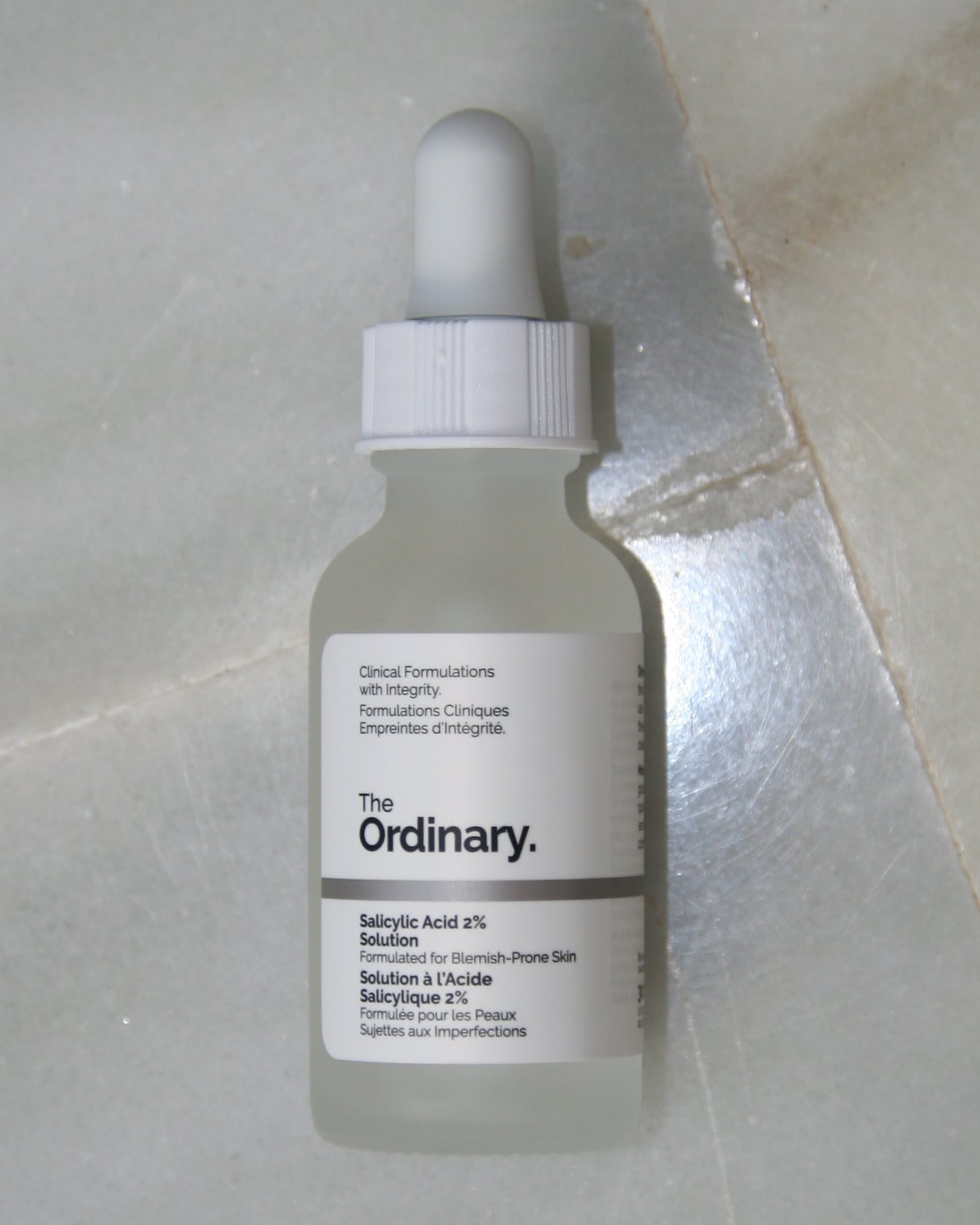 The Ordinary Salicylic Acid 2% Solution frosted dropper bottle lying on grey marble