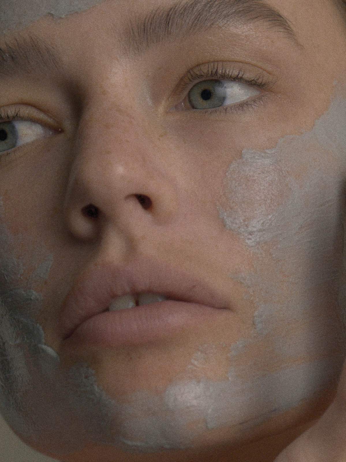 Model with a pale clay mask across her face in a skincare portrait