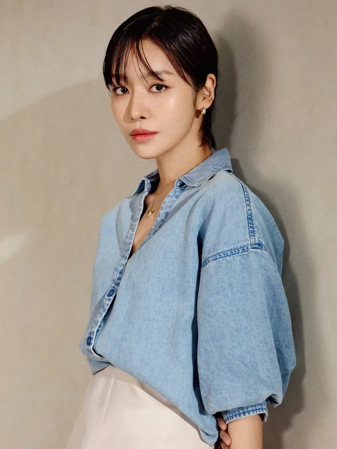 Cha Joo Young in a relaxed denim shirt and ivory skirt against a light stone wall