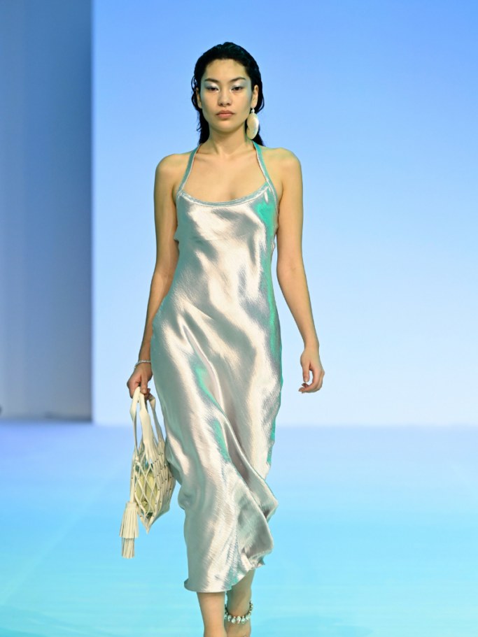 Model walks the runway in a metallic silver slip dress and jeweled sandals