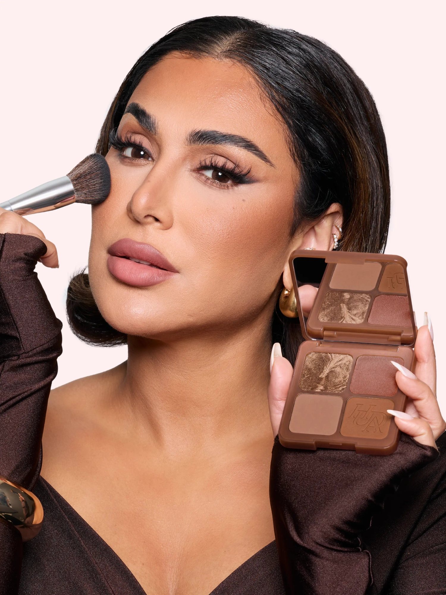 Woman applying bronzer with a brush and holding an open palette