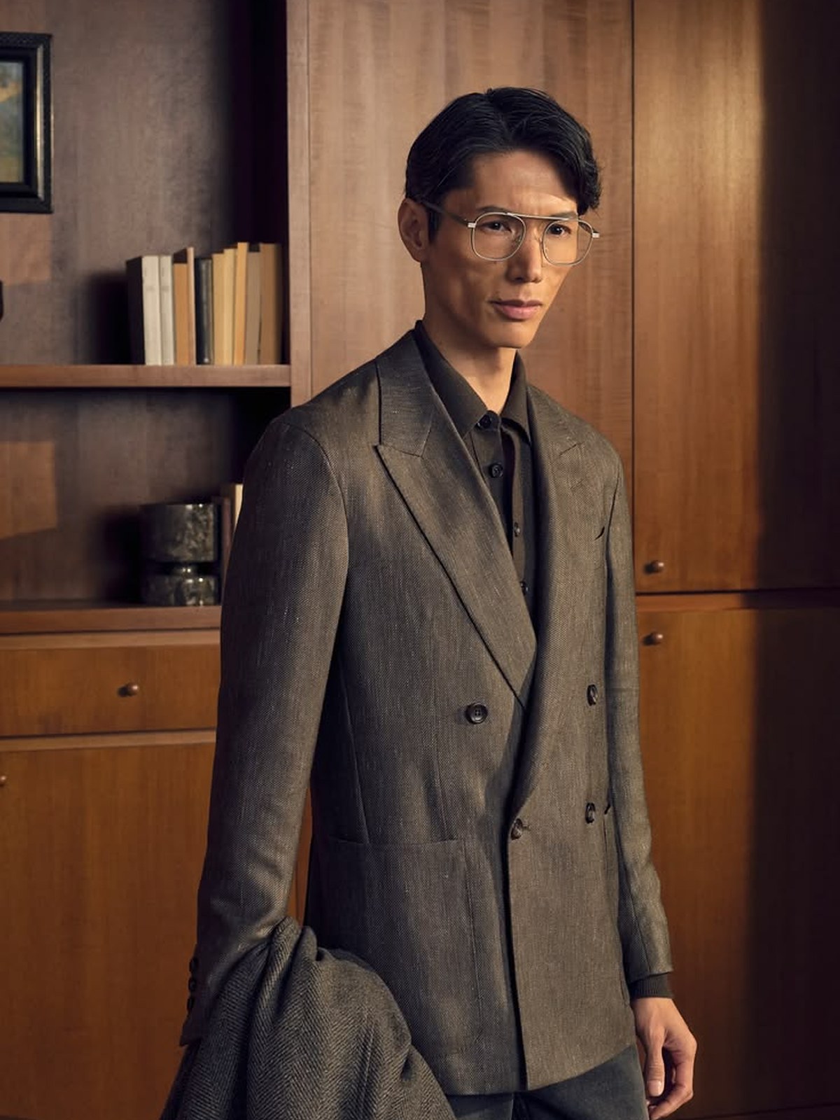 Man in a dark double breasted suit in a wood paneled room