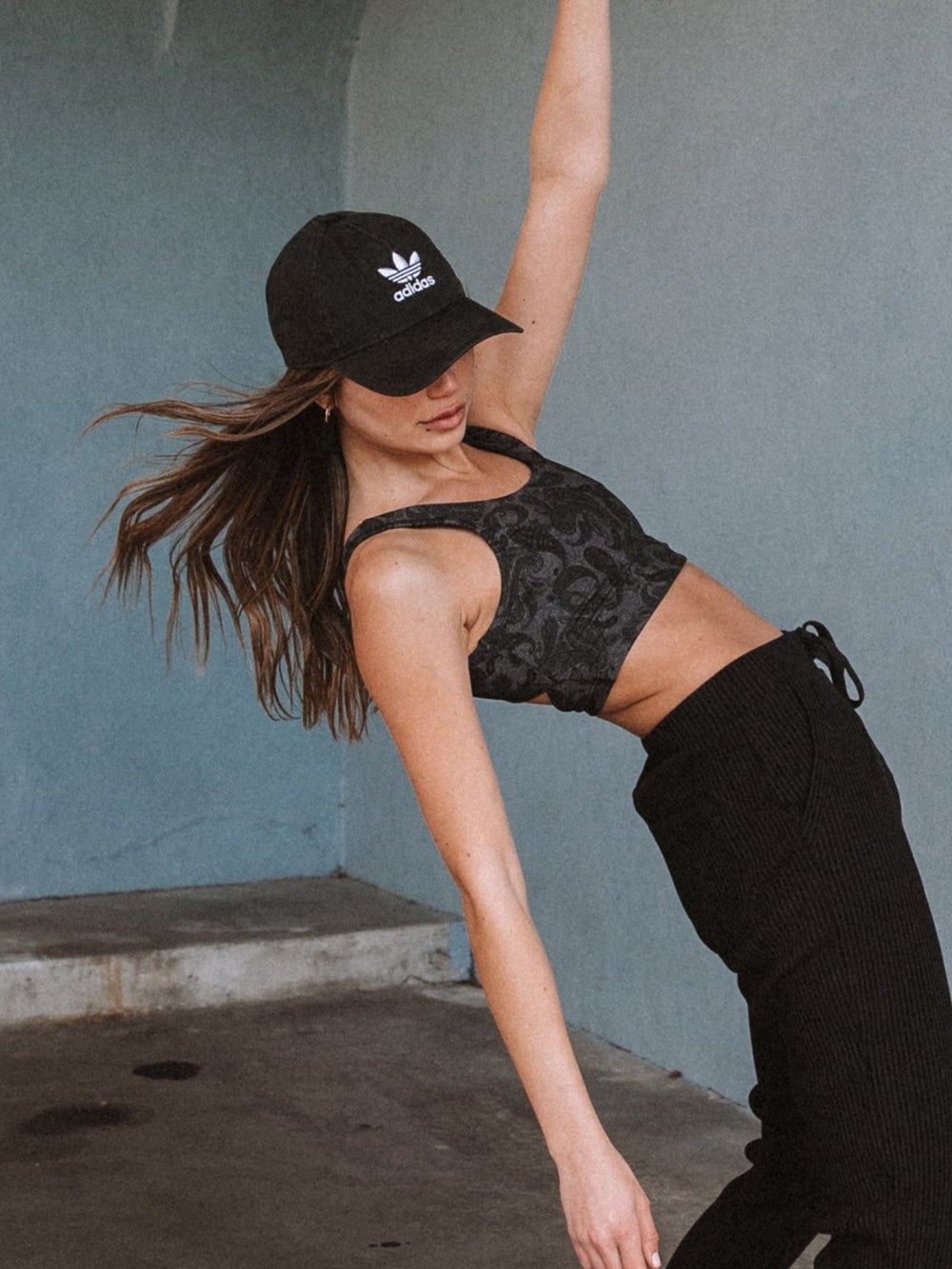 Model in black STRUT-THIS activewear against a blue studio wall