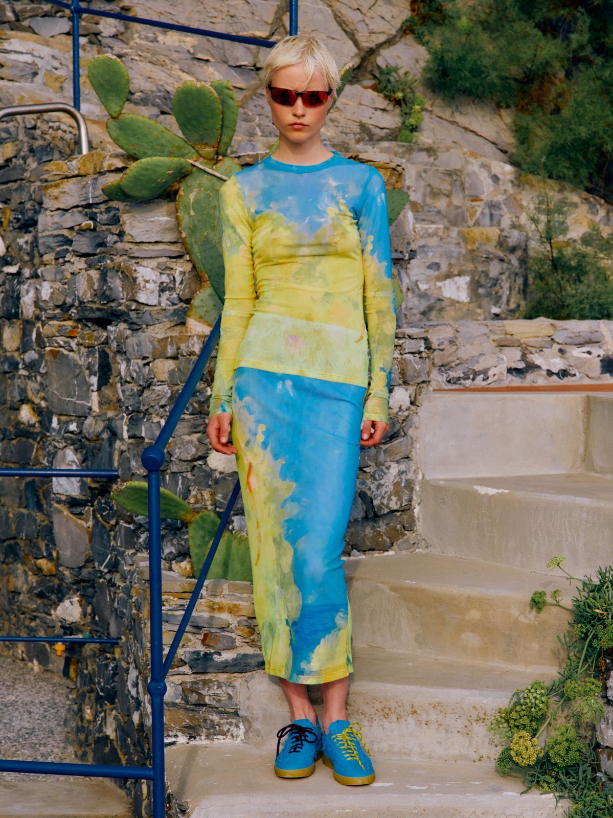 Model in a colorful printed MSGM dress against garden stonework