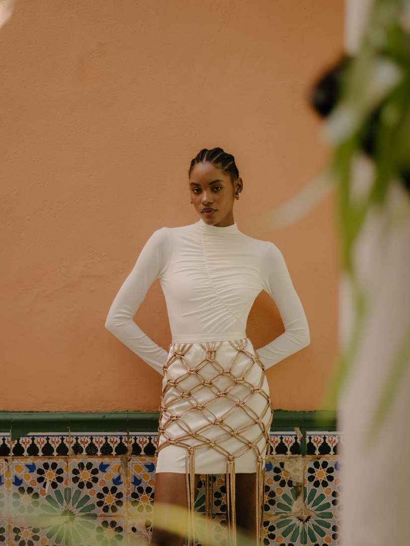 Model in white textured separates against a coral courtyard wall