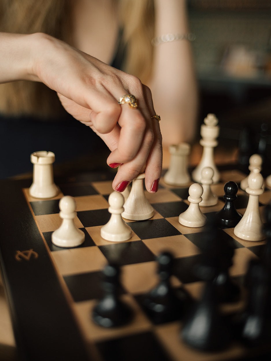 Close-up of a hand moving a wooden chess piece