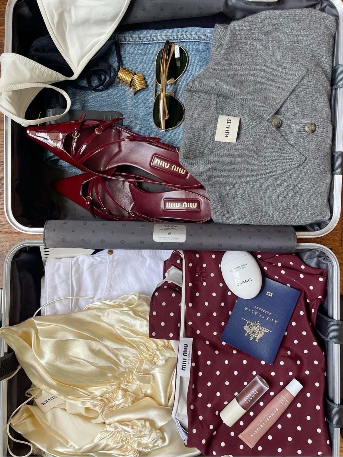 A suitcase packed with red heels, a grey jacket and a satin skirt