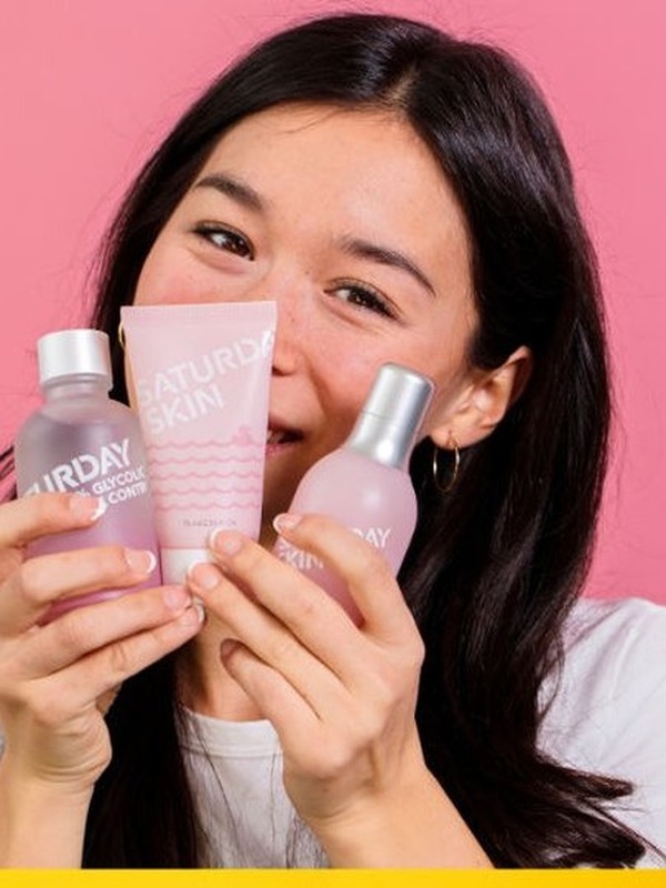 Woman smiling while holding Saturday Skin products
