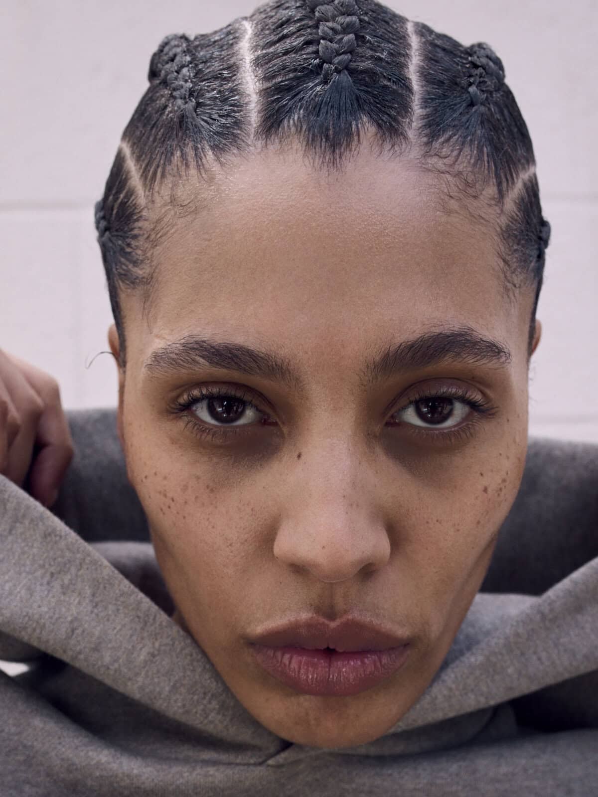 Woman in a grey hooded sweatshirt in a close ESSENTIALS campaign portrait