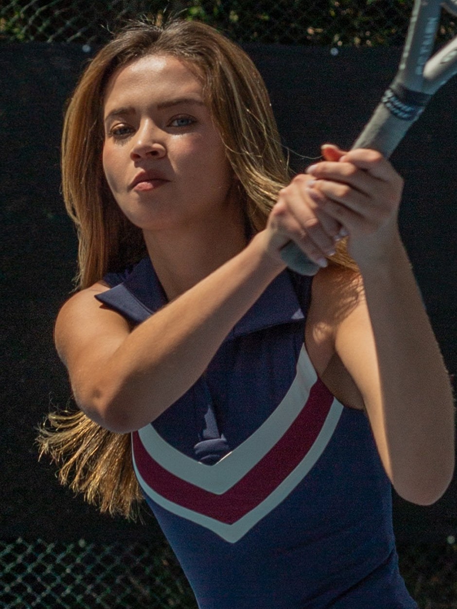 Model holding a tennis racket in a navy and burgundy court look