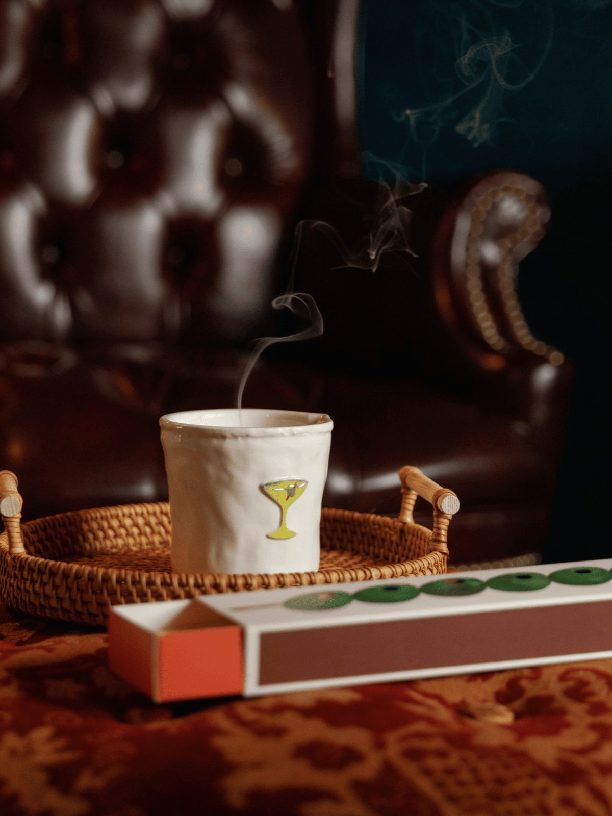 Cocktail illustrated ceramic candle in a wicker tray in a moody room