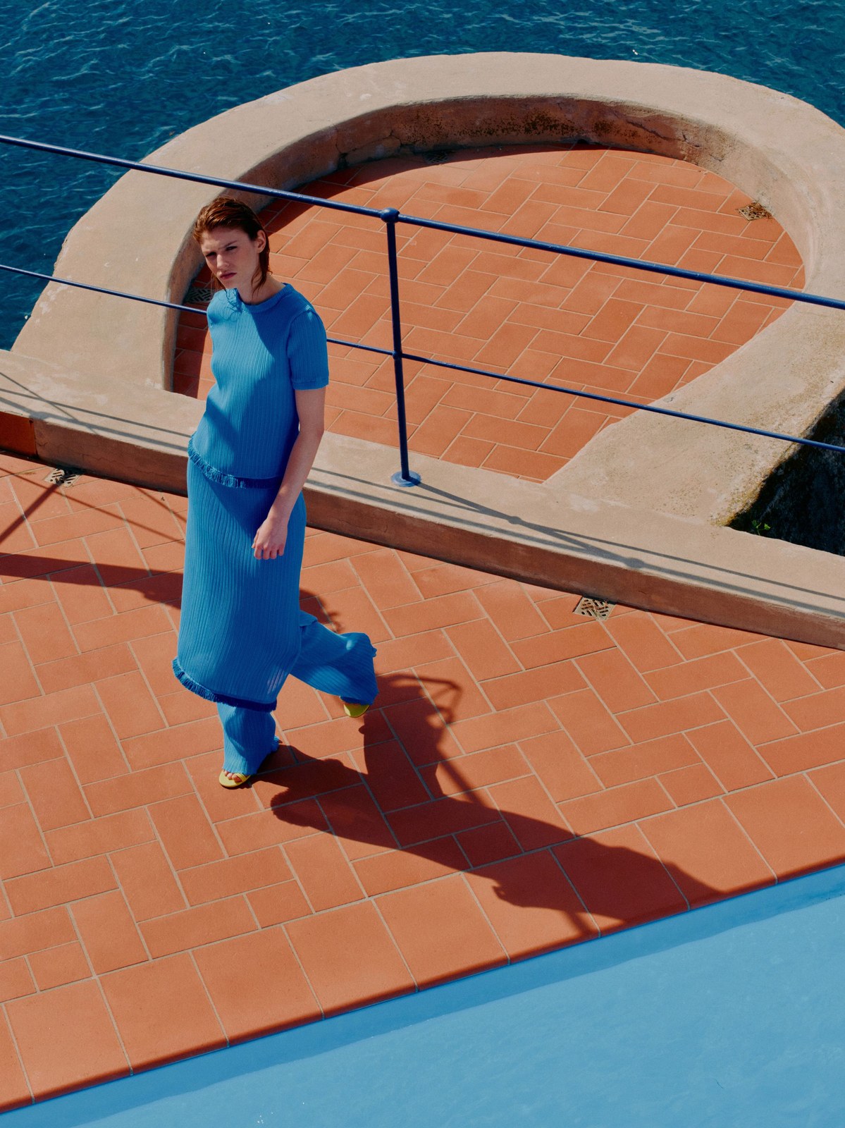Model in a bright blue knit look beside a pool