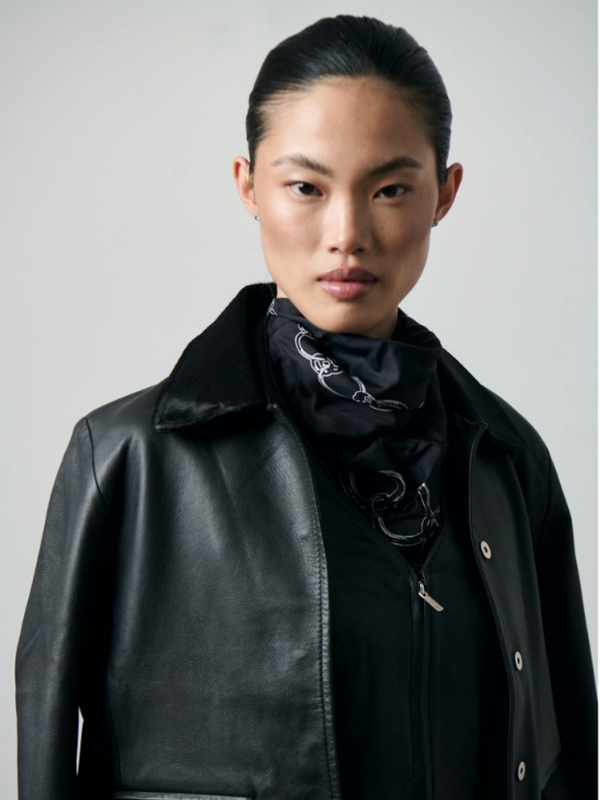 Model wearing a black leather jacket and scarf