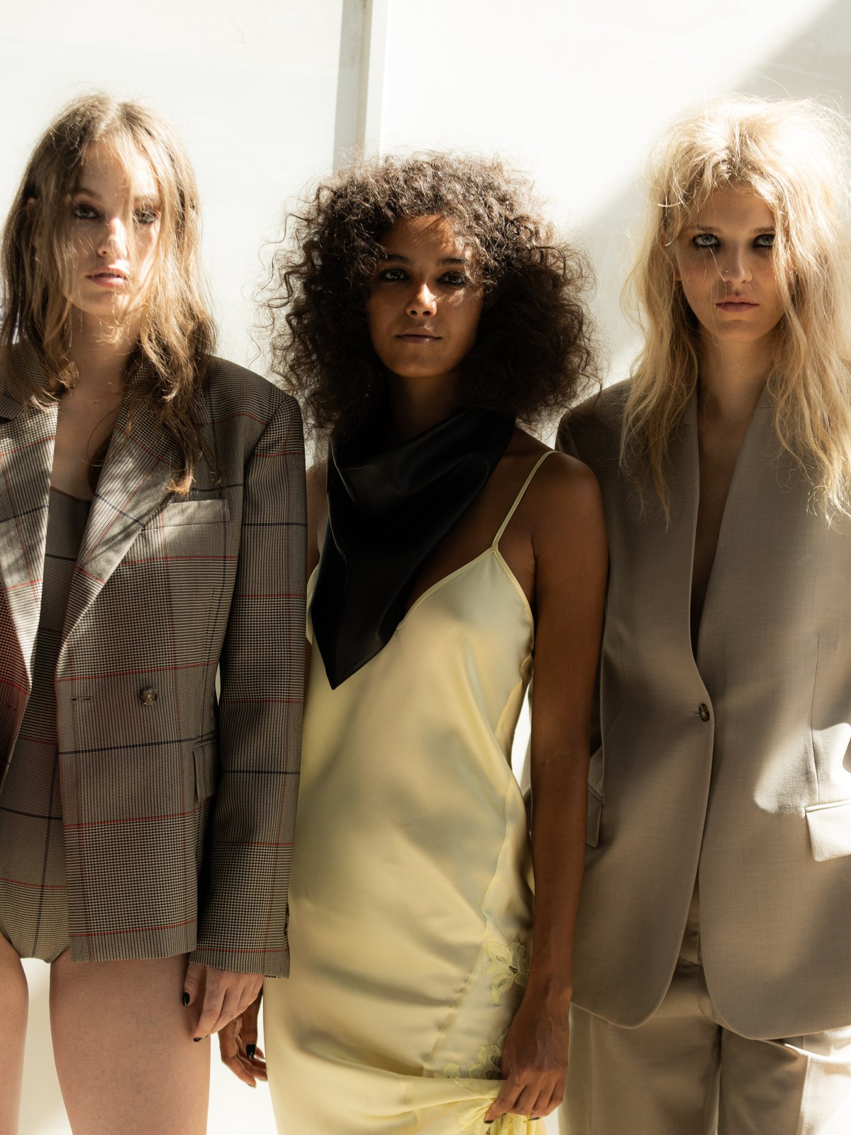Three HERSKIND models in contrasting sheer, tailored, and satin looks