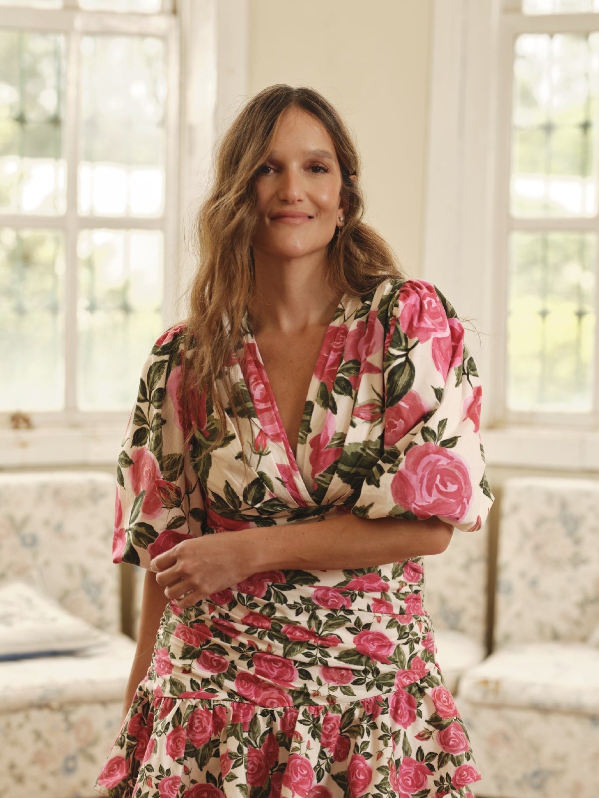 Model in a floral puff sleeve mini dress in a sunny sitting room