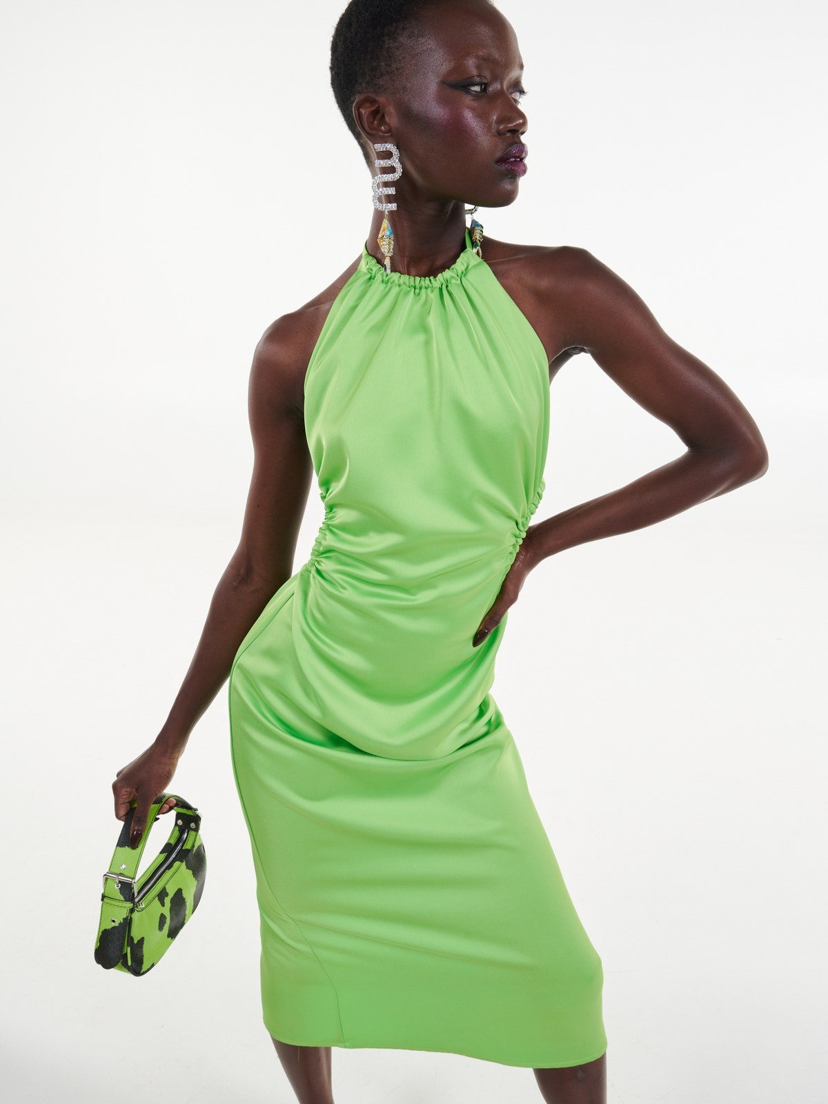 Model in a lime green dress with a printed clutch