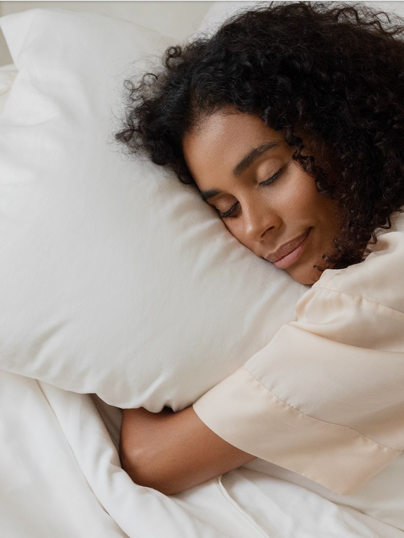 Woman resting on a white pillow in pale sleepwear