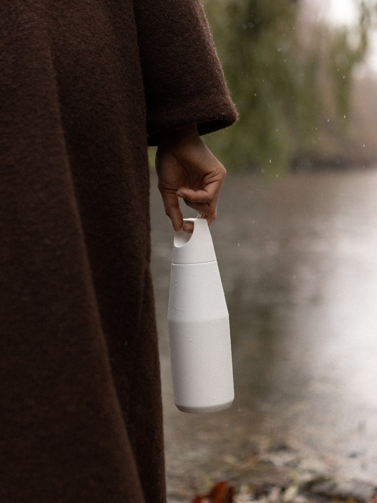 A person carries a white bottle along a wooded path