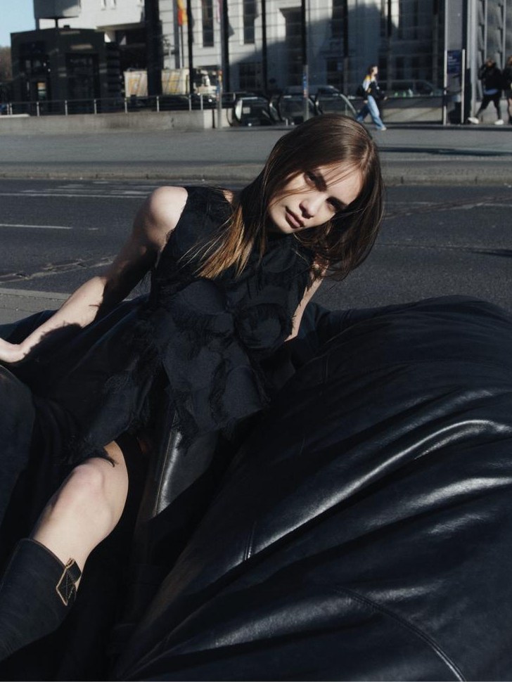 Woman in a black textured dress reclining on a sculptural black seat in Potsdamer Platz