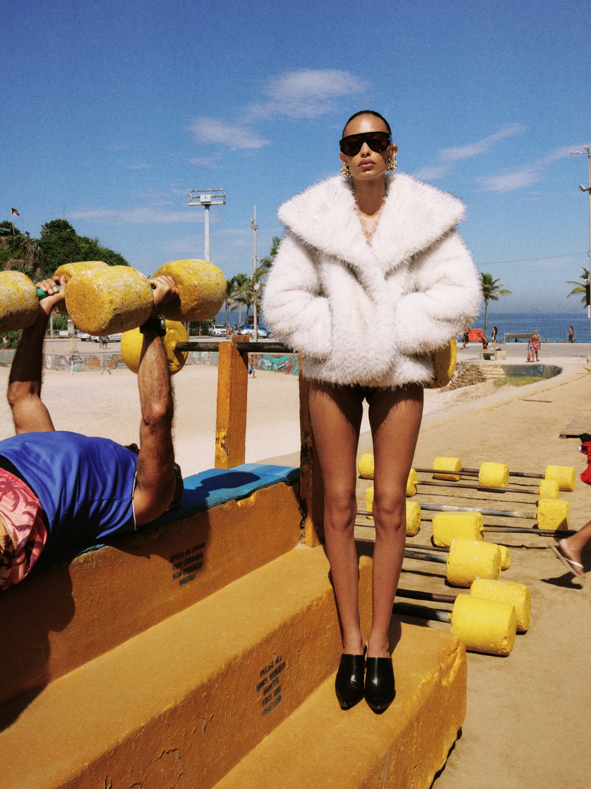 Model in a white faux-fur coat on a colorful seaside promenade