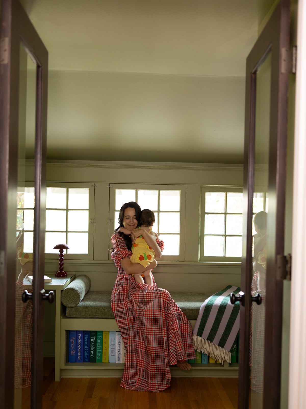 Rachel Hochhauser in a colorful dress at home with a child