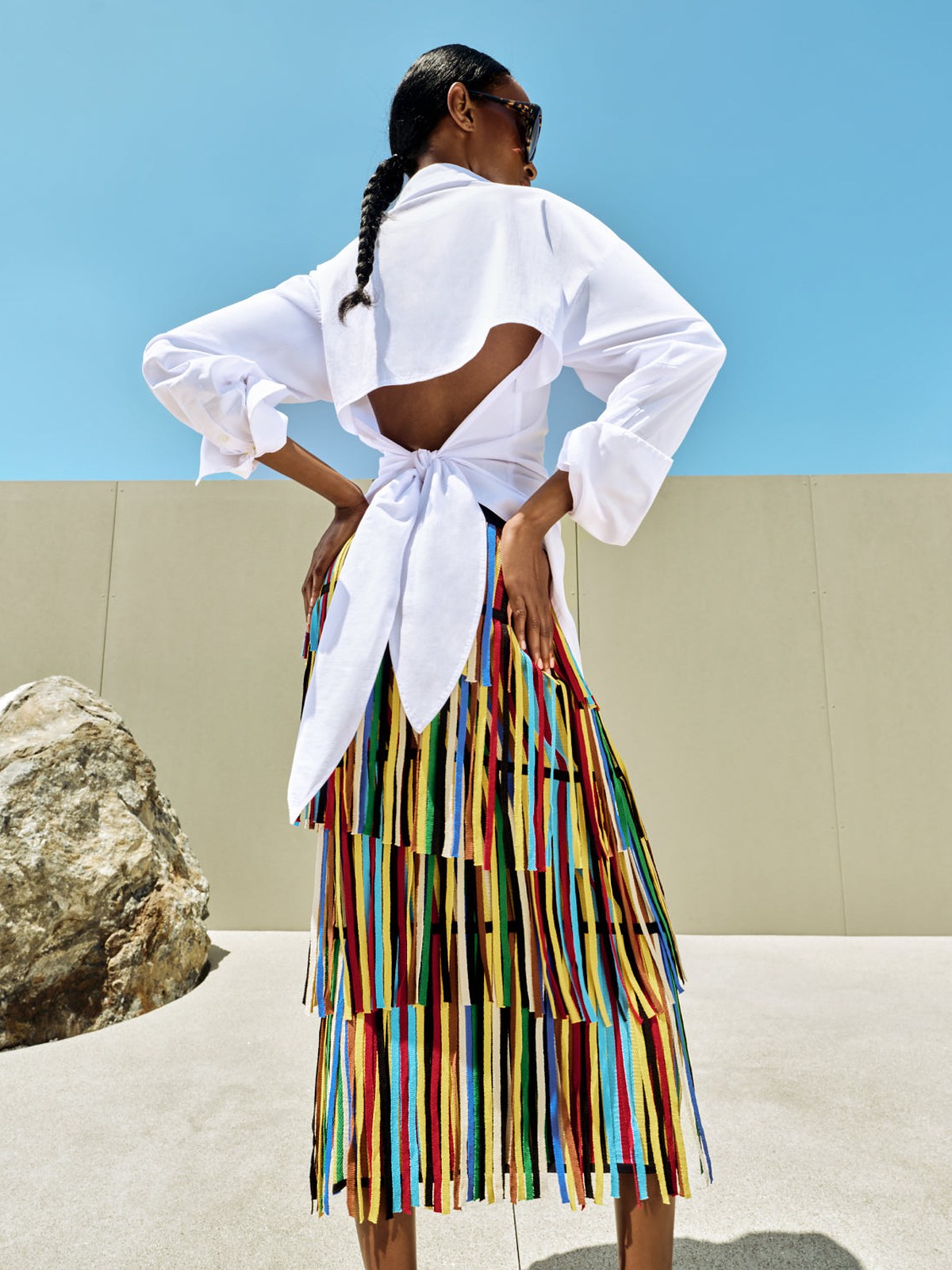 Model from behind in a white tie back blouse and striped skirt