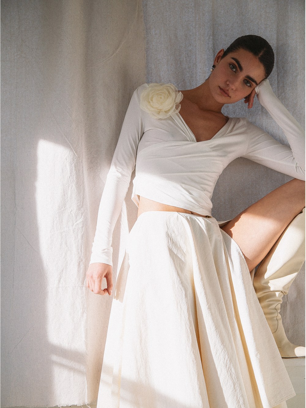 Model in a white long sleeve top and full skirt in a sunlit room