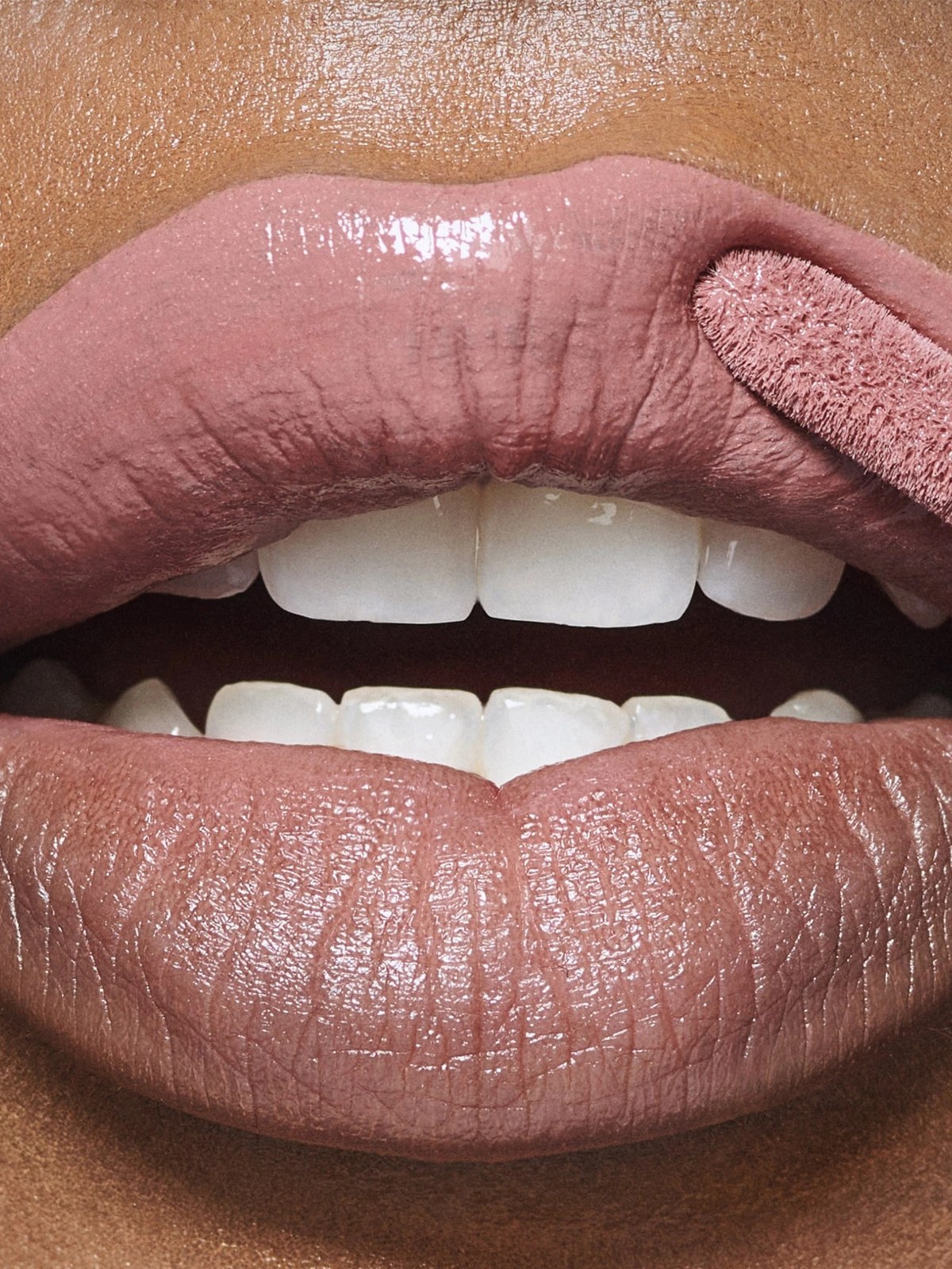 Close up of glossy nude pink lips with a wand applicator