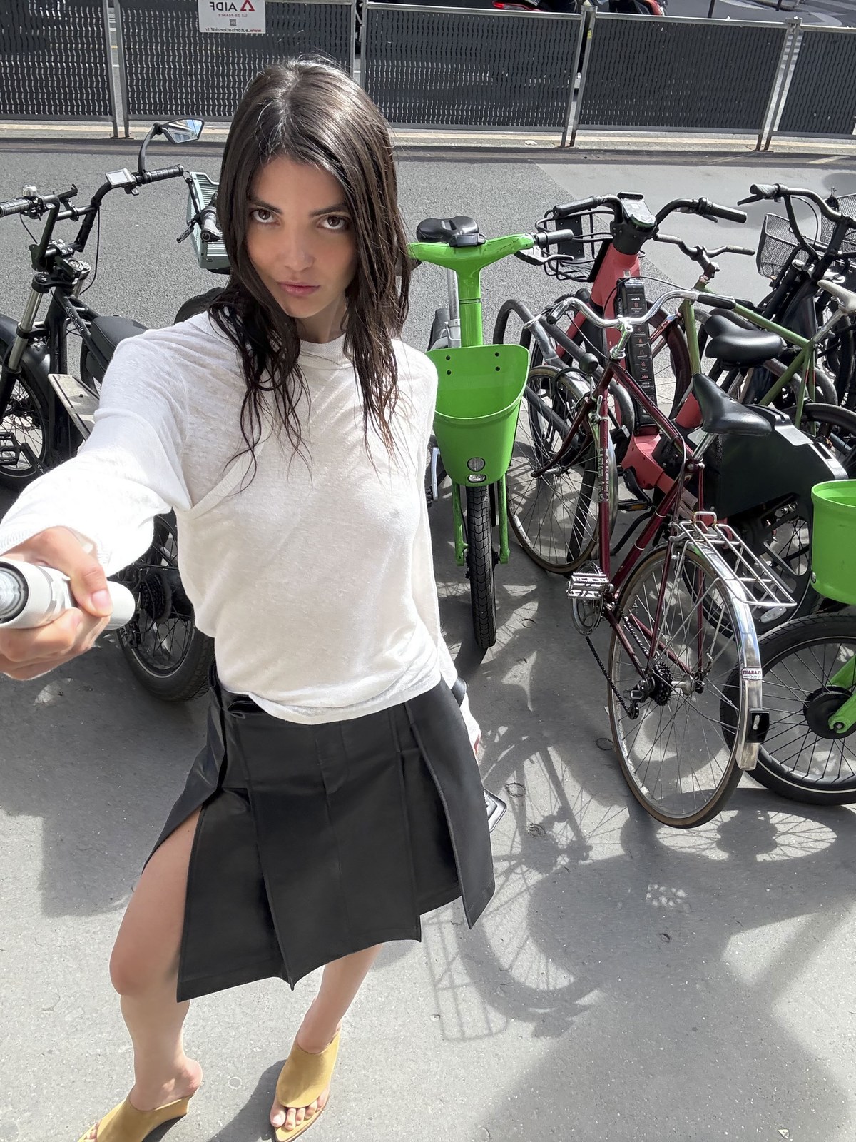 Model in a white top and dark skirt among city bicycles