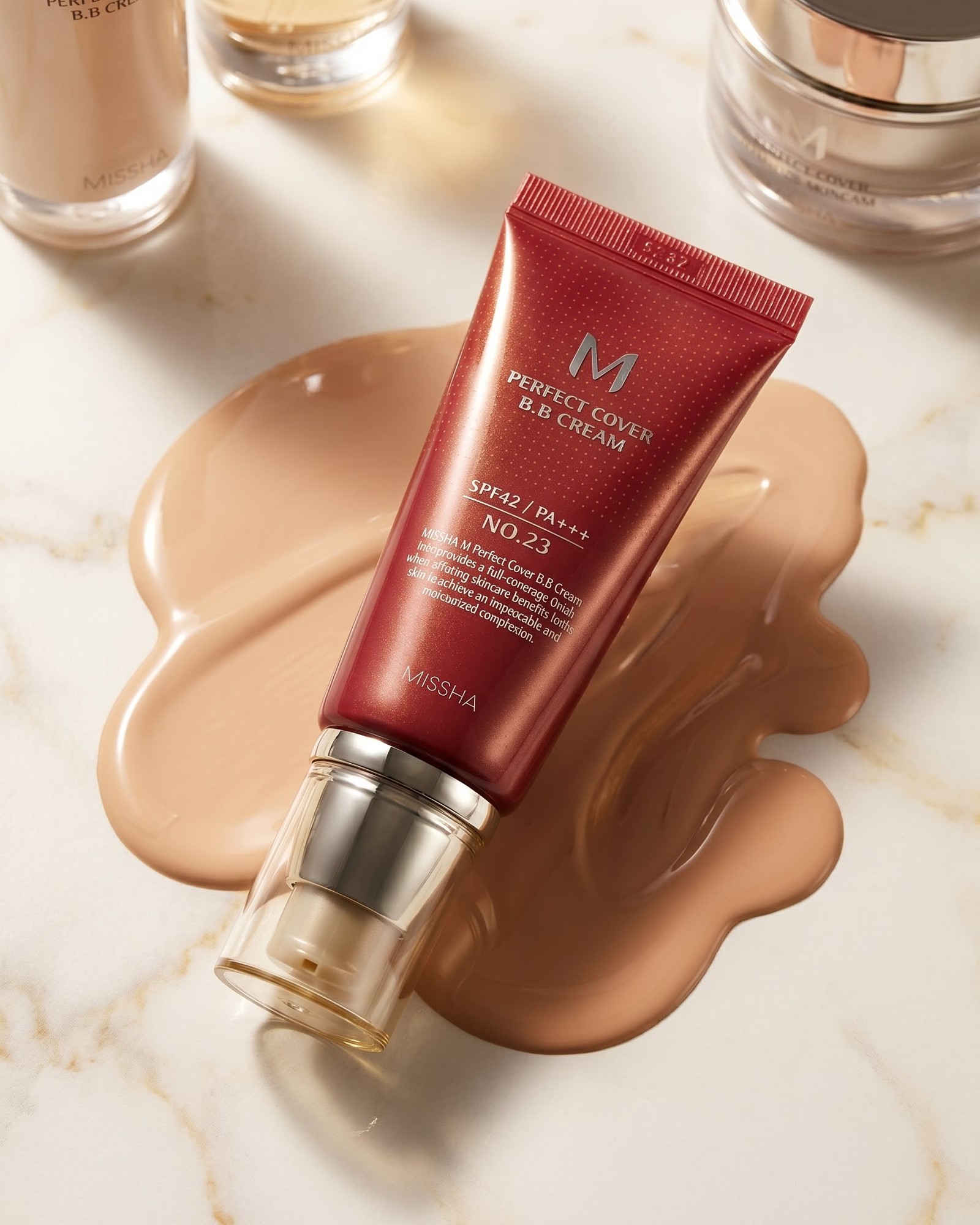 MISSHA M Perfect Cover BB Cream tube in red lying on white marble over a smear of beige cream